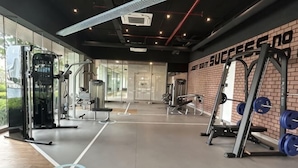 A gym with weightlifting equipment, a brick wall, and a large window. - KL Central 31st floor KLCC view (Kuala Lumpur)