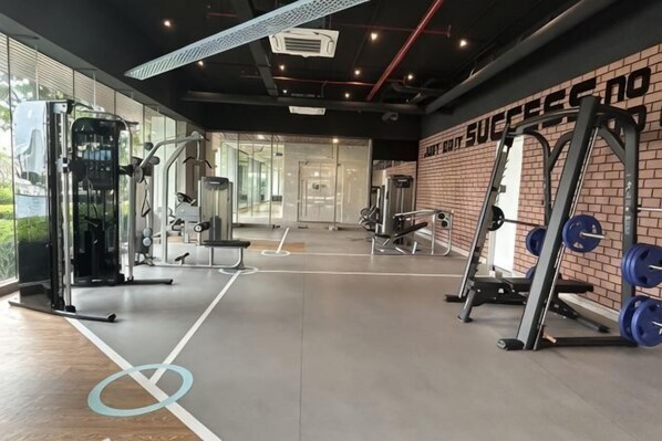 A gym with weightlifting equipment, a brick wall, and a large window. - KL Central 31st floor KLCC view (Kuala Lumpur)