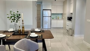 A modern dining area with a table set for four, a plant, candles, and a pendant light. - KL Central 31st floor KLCC view (Kuala Lumpur)