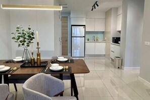 Een moderne eethoek met een tafel gedekt voor vier personen, een plant, kaarsen en een hanglamp.