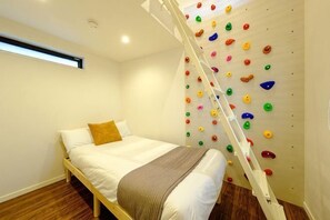 A bedroom with a bed, a climbing wall, and a wooden ladder. - Higashi Nakano Monthly House (Tokyo)