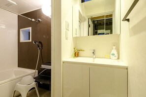 A bathroom with a bathtub, a shower, a sink with a mirror, and a toilet. - Higashi Nakano Monthly House (Tokyo)