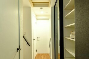 A narrow hallway with a wooden floor leading to a door at the end. - Higashi Nakano Monthly House (Tokyo)