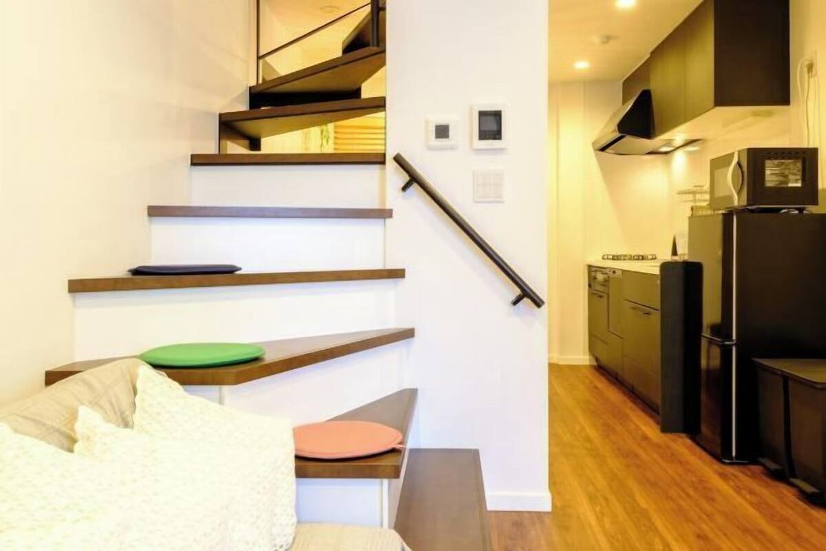 Un escalier mène à une cuisine au design moderne, à un coin repas avec une table et des chaises, et à un banc intégré.