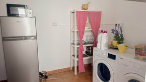 A compact kitchen with a refrigerator, microwave, and washing machine.