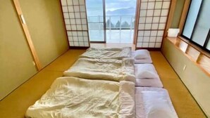 Een traditionele Japanse kamer met tatami vloerbedekking, verschuifbare shoji deuren en uitzicht op een berg.