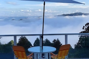 A table with two chairs and an umbrella, overlooking a mountainous landscape with clouds. - Atami Tenku Villa Sky terrace (Atami)