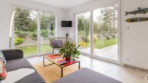Una sala de estar moderna con un sofá, una mesa de centro con una planta y un televisor montado en la pared.