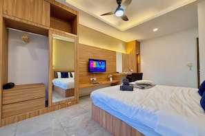 Een moderne hotelkamer met een bed, een televisie, een kledingkast en een plafondventilator.