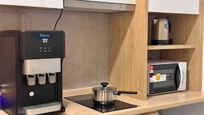 Une cuisine équipée d’une machine à café, d’un four à micro-ondes et d’une casserole posée sur le plan de travail.