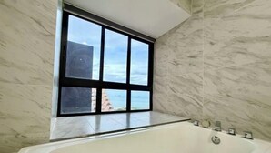 Une salle de bain dotée d’une grande fenêtre, d’une baignoire et de murs en marbre.