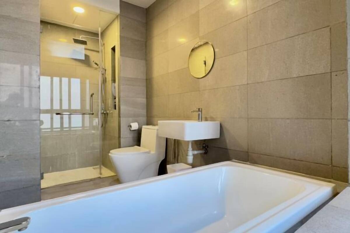 Une salle de bain moderne équipée d’une baignoire, de toilettes et d’un espace douche.