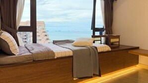 Une chambre moderne dotée d’une grande fenêtre, d’un banc en bois, d’une petite table et d’un lit offrant une vue sur la mer.