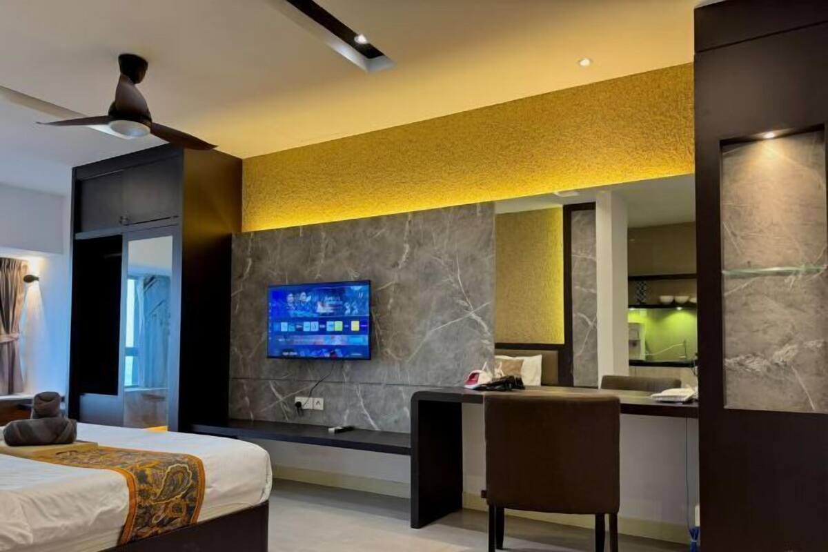 Une chambre d’hôtel moderne équipée d’un lit, d’un bureau, d’une télévision et d’une salle de bain avec un miroir.