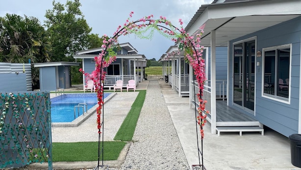 A pool area with a clear pathway, a gazebo, and a row of cabins. - Capital O 91228 Hureen Chalet Hmk (Arau)