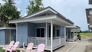 A small, single-story building with a porch, two pink chairs, and a small outdoor seating area. - Capital O 91228 Hureen Chalet Hmk (Arau)