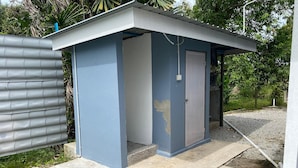A small, single-room structure with a door and a window, surrounded by a concrete base and a metal fence. - Capital O 91228 Hureen Chalet Hmk (Arau)