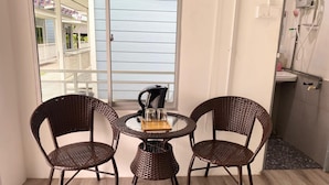 A balcony with wicker chairs, a small table, and a kettle. - Capital O 91228 Hureen Chalet Hmk (Arau)