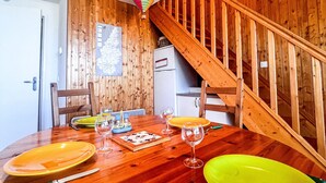 Een houten eettafel met borden, glazen en bestek. Een houten trap is rechts zichtbaar.