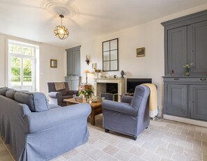 Un salon avec une cheminée, des meubles gris et un grand meuble de rangement gris.