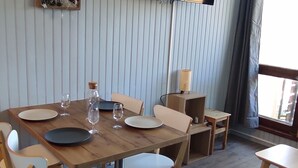 Un coin repas avec une table en bois, des chaises et un téléviseur fixé au mur.