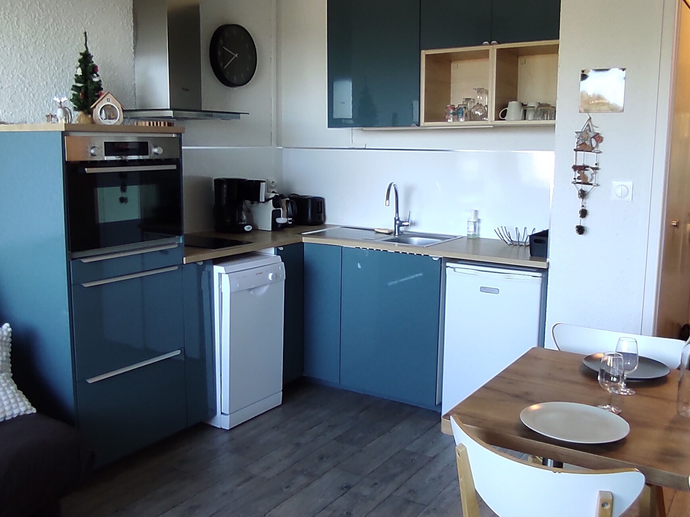 Een kleine keuken met een vaatwasser, oven en koffiezetapparaat.