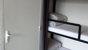 Una cama litera con almohadas estampadas y una puerta blanca con manija.