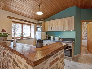 A kitchen with wooden cabinets, a stone countertop, and a window with plants.