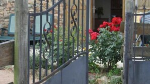 A stone building with a metal gate and red flowers in the foreground. - Country cottage with pets allowed near Roanne (Neulise)