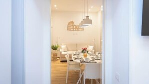 Un interior moderno con comedor, muebles blancos e iluminación colgante.