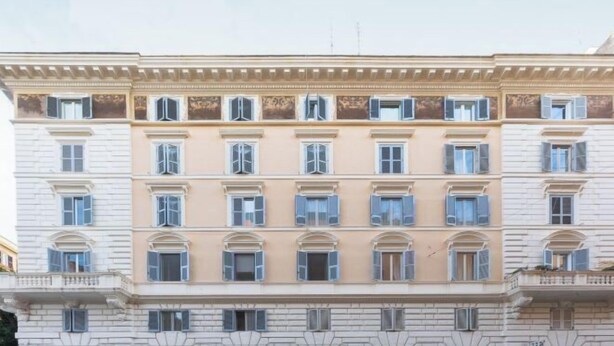 Un edificio de varios pisos con estilo arquitectónico clásico, que presenta una fachada simétrica con ventanas regularmente distribuidas y molduras decorativas.