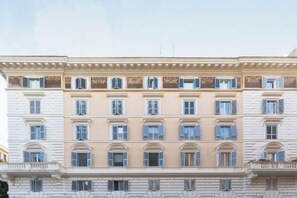 A multi-story building with a classical architectural style, featuring a symmetrical facade with evenly spaced windows and a central entrance. - Colosseum Holidays - Three-Bedroom Apartment (Rome)