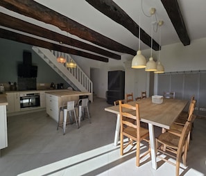 A spacious kitchen with a central island, wooden chairs, and pendant lighting.