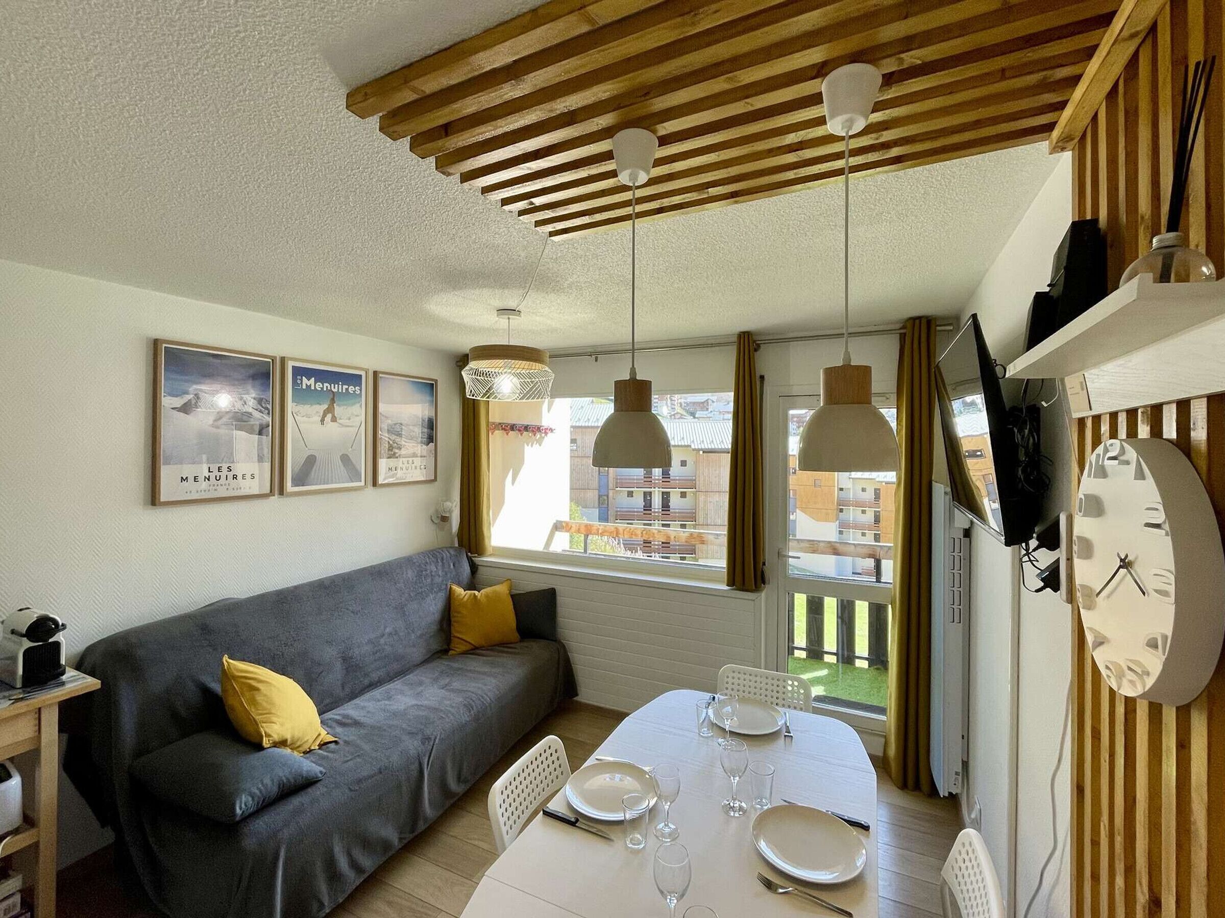 A cozy living room with a sofa, dining table, and hanging pendant lights.
