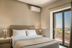 Une chambre d’hôtel avec un lit, des tables de chevet et une vue sur un balcon extérieur, accessible par une porte-fenêtre coulissante.
