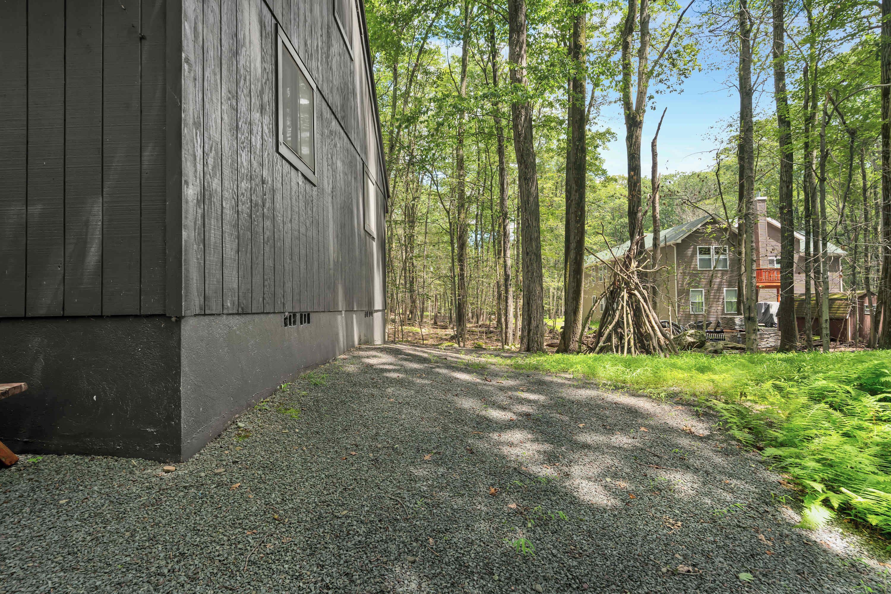 A wooden building with a gravel path leading to a forested area.