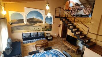 Una sala acogedora con un sofá, una mesa de comedor y una escalera.