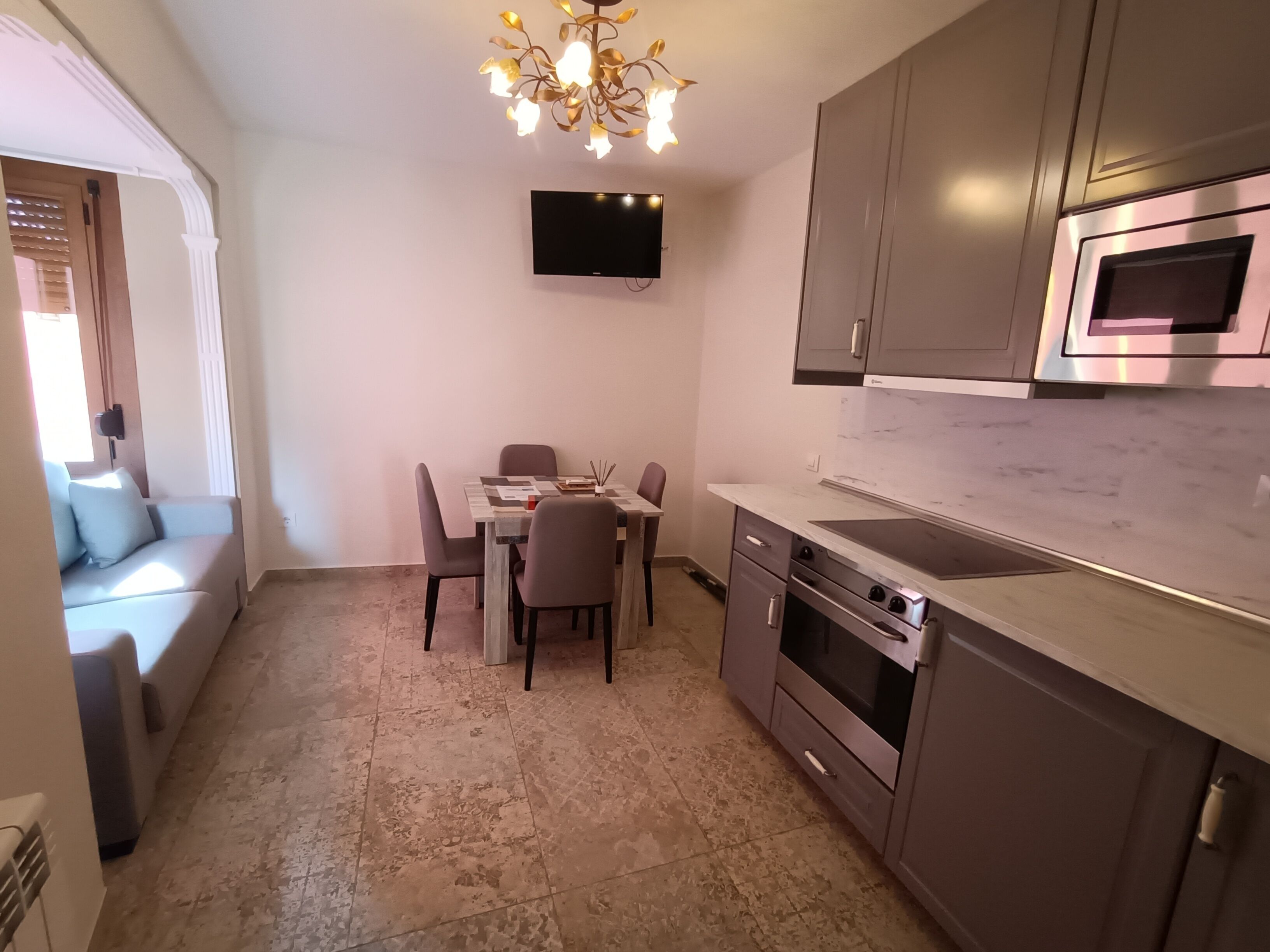 Una cocina compacta con comedor, televisor de pantalla plana, electrodomésticos modernos y un candelabro decorativo.