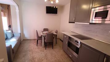Una cocina compacta con comedor, televisor de pantalla plana, electrodomésticos modernos y un candelabro decorativo.