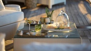 A glass-top table with a tray holding a drink, a small bowl, a candle, and a decorative item. - Point Residence (Auckland)
