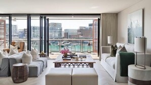 A modern hotel room with a balcony, a sofa set, a coffee table, and a view of the cityscape and water. - Point Residence (Auckland)
