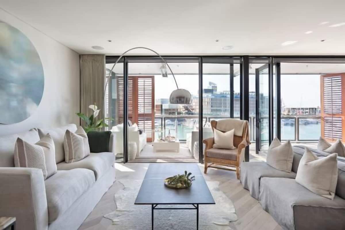 A modern living room with a sofa set, a coffee table, and a view of the city through large windows.