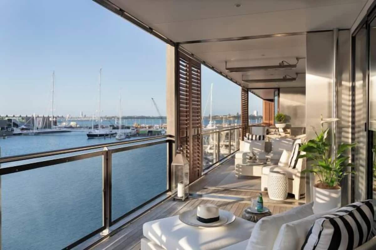 A balcony with a view of the marina, furnished with sofas and a table, and a potted plant.