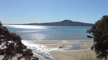 Uma praia com águas cristalinas, areia dourada e uma colina ao longe.