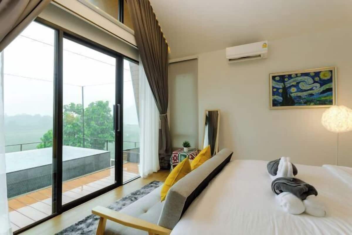 Una camera d'albergo moderna con un letto grande, un quadro appeso al muro e un balcone con vista.