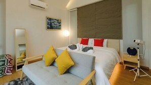 A modern hotel room with a large bed, a sofa, a bedside table, and a mirror. - Pause pausa (Phrao)