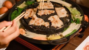 A hot plate with grilled meat, vegetables, and a bowl of eggs. - Pause pausa (Phrao)
