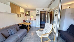 A compact living space with a sofa, a dining table, and a kitchen area.