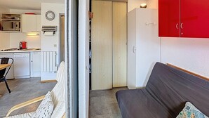 A compact living space with a kitchenette, a dining area, and a red wardrobe.