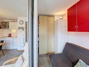 Um espaço de estar compacto com cozinha compacta, área de refeições e guarda-roupa vermelho.